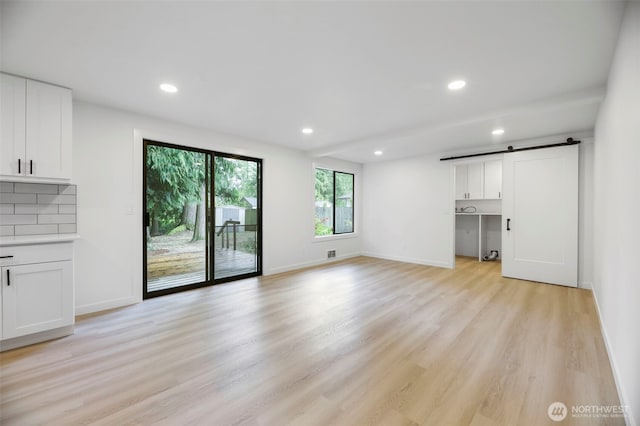 9828 33rd Dr SE, Everett, WA 98208 - unfurnished living room with a barn door, light wood-style flooring, recessed lighting, and baseboards
