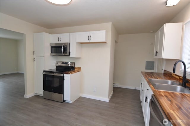 3159 Florida St, Longview, WA 98632 - kitchen featuring appliances with stainless steel finishes, wooden counters, a sink, white cabinetry, and wood finished floors