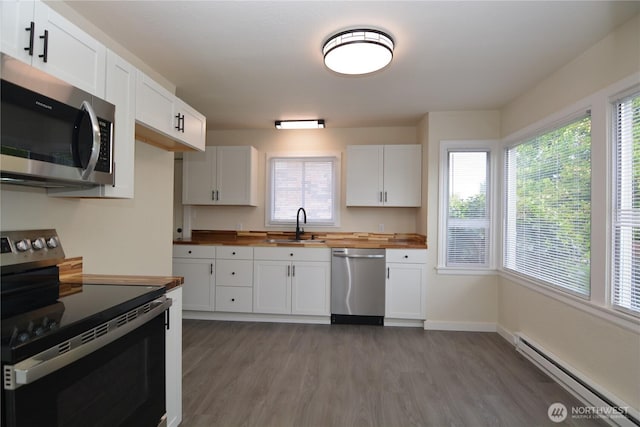 3159 Florida St, Longview, WA 98632 - kitchen with appliances with stainless steel finishes, wooden counters, a baseboard heating unit, a sink, and wood finished floors