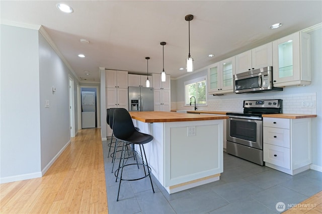 7519 221st Pl SW, Edmonds, WA 98026 - kitchen with butcher block countertops, appliances with stainless steel finishes, white cabinetry, crown molding, and decorative backsplash