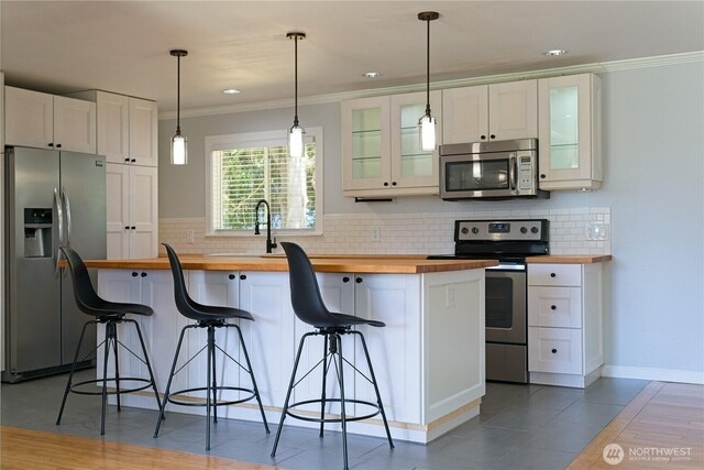 7519 221st Pl SW, Edmonds, WA 98026 - kitchen with stainless steel appliances, butcher block counters, ornamental molding, white cabinets, and decorative backsplash