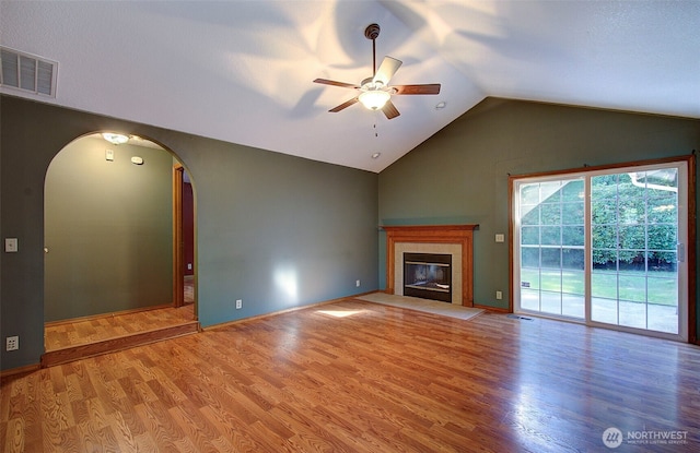 10010 NE 76th Cir, Vancouver, WA 98662 - unfurnished living room featuring ceiling fan, vaulted ceiling, wood finished floors, arched walkways, and a tile fireplace