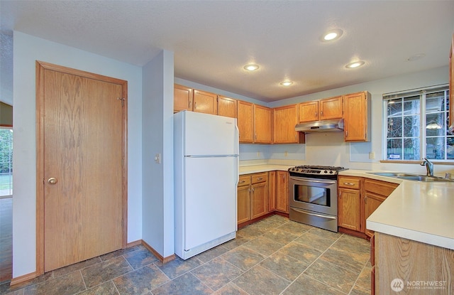 10010 NE 76th Cir, Vancouver, WA 98662 - kitchen with freestanding refrigerator, stainless steel gas stove, dark stone finish floors, under cabinet range hood, and light countertops