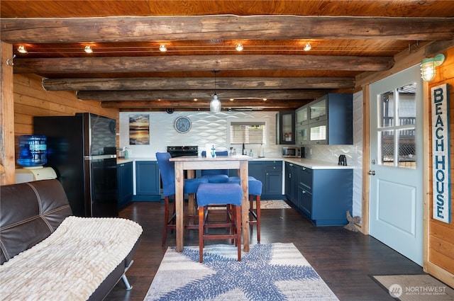 270 E Grapeview Point Rd, Allyn, WA 98524 - kitchen featuring freestanding refrigerator, stainless steel microwave, dark wood finished floors, light countertops, and wooden ceiling with exposed beams