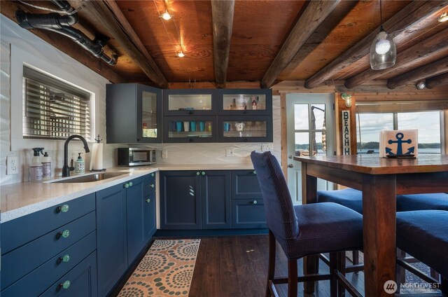 270 E Grapeview Point Rd, Allyn, WA 98524 - kitchen with a sink, blue cabinets, dark wood-style floors, light countertops, and wooden ceiling with exposed beams