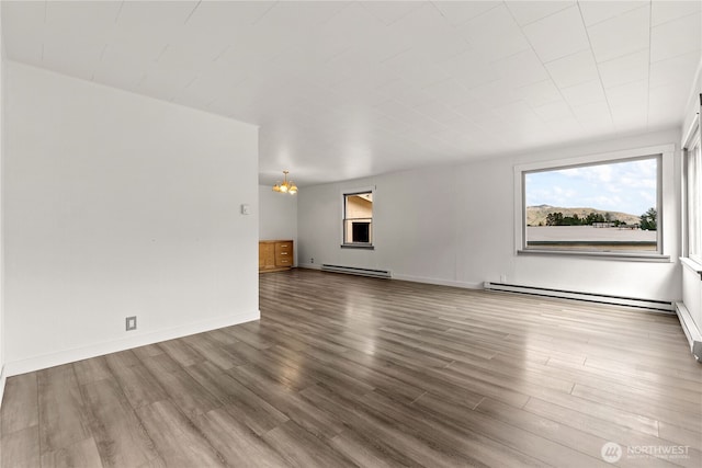 318 Lombard St, Twisp, WA 98856 - unfurnished living room with baseboard heating, plenty of natural light, a chandelier, and wood finished floors