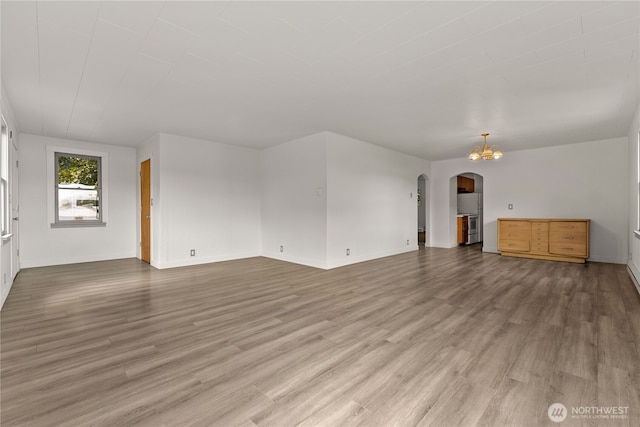 318 Lombard St, Twisp, WA 98856 - unfurnished living room with arched walkways, wood finished floors, baseboards, and a chandelier