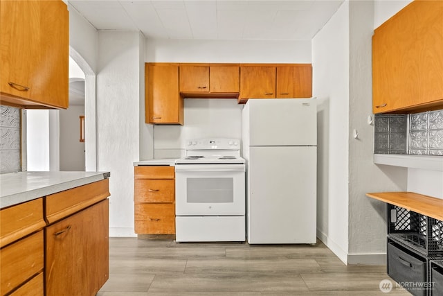 318 Lombard St, Twisp, WA 98856 - kitchen with white appliances, light countertops, light wood-style floors, brown cabinetry, and arched walkways