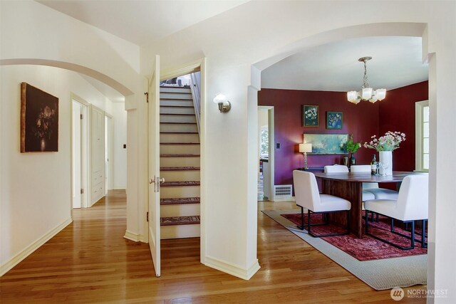 1635 46th Ave SW, Seattle, WA 98116 - dining space featuring wood finished floors, arched walkways, a chandelier, stairway, and baseboards