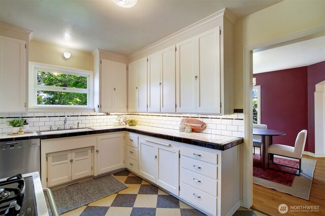 1635 46th Ave SW, Seattle, WA 98116 - kitchen with a sink, tile countertops, tasteful backsplash, stainless steel dishwasher, and light floors