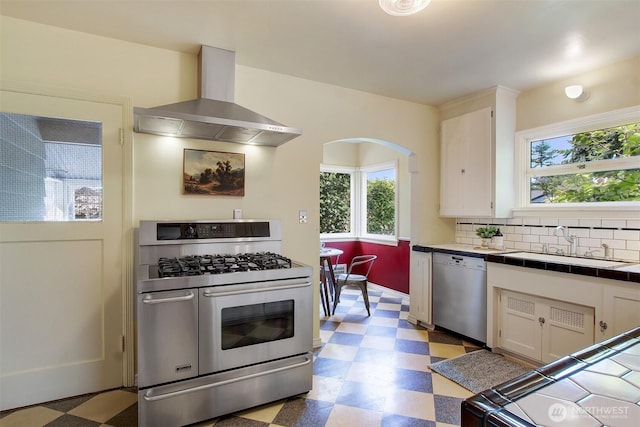 1635 46th Ave SW, Seattle, WA 98116 - kitchen with appliances with stainless steel finishes, wall chimney exhaust hood, tile countertops, light flooring, and a sink