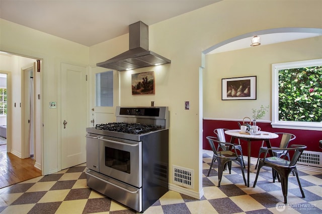 1635 46th Ave SW, Seattle, WA 98116 - kitchen with range with two ovens, tile patterned floors, wall chimney range hood, and plenty of natural light