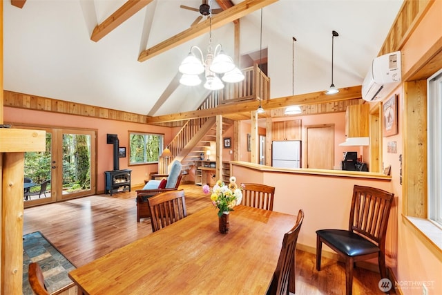 7480 Glacier Springs Dr, Deming, WA 98244 - dining area with a wood stove, a wall unit AC, a chandelier, stairway, and high vaulted ceiling