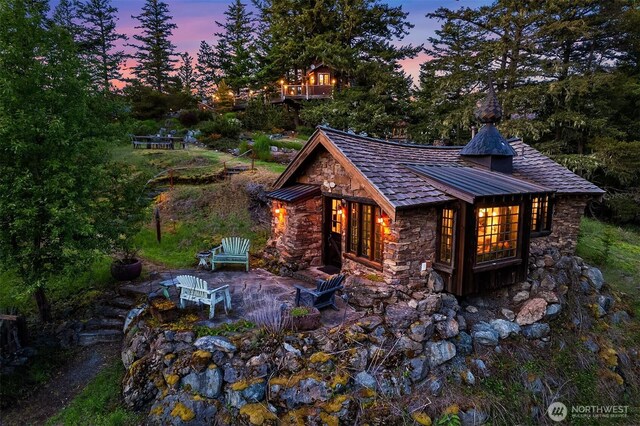 354 Nighthawk Ln, Orcas Island, WA 98279 - back of house with stone siding, a standing seam roof, a patio, and metal roof