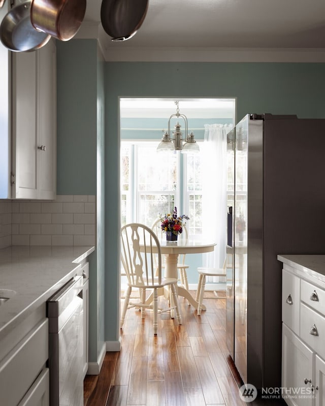 1701 W Yakima Ave, Yakima, WA 98902 - kitchen with appliances with stainless steel finishes, white cabinetry, wood finished floors, a chandelier, and decorative backsplash