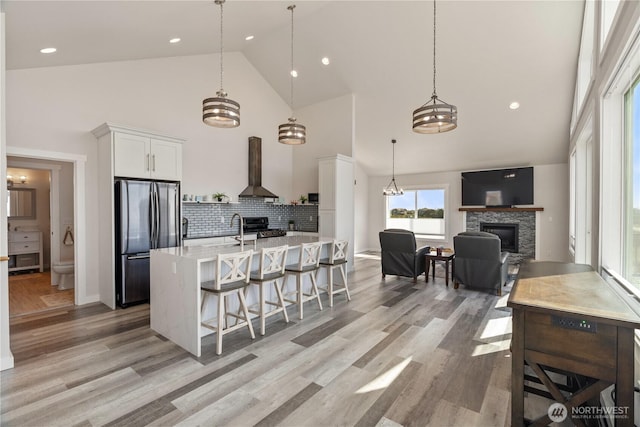 1438 Ocean Crest Ave SW, Ocean Shores, WA 98569 - kitchen featuring stainless steel appliances, high vaulted ceiling, island range hood, a stone fireplace, and light countertops