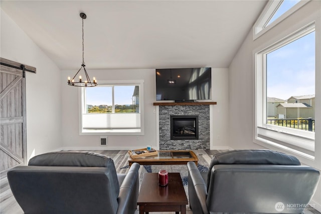 1438 Ocean Crest Ave SW, Ocean Shores, WA 98569 - living area featuring lofted ceiling, wood finished floors, a barn door, a stone fireplace, and a chandelier
