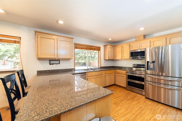 14415 144th St E, Orting, WA 98360 - kitchen featuring appliances with stainless steel finishes, light brown cabinetry, a peninsula, dark stone countertops, and light wood-style floors