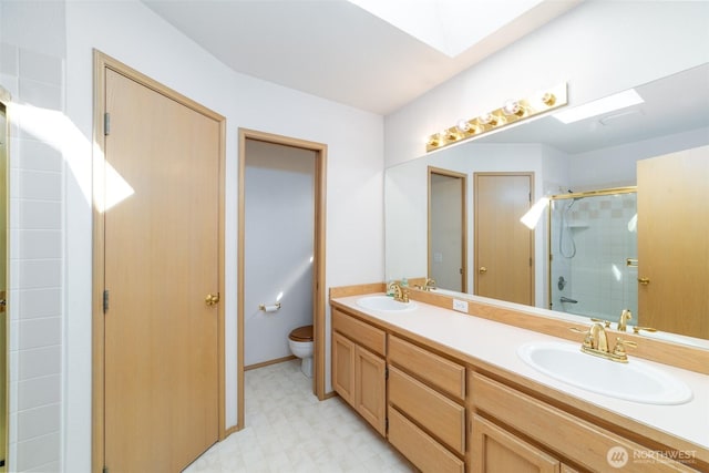 14415 144th St E, Orting, WA 98360 - bathroom featuring a skylight, double vanity, a shower stall, tile patterned floors, and toilet