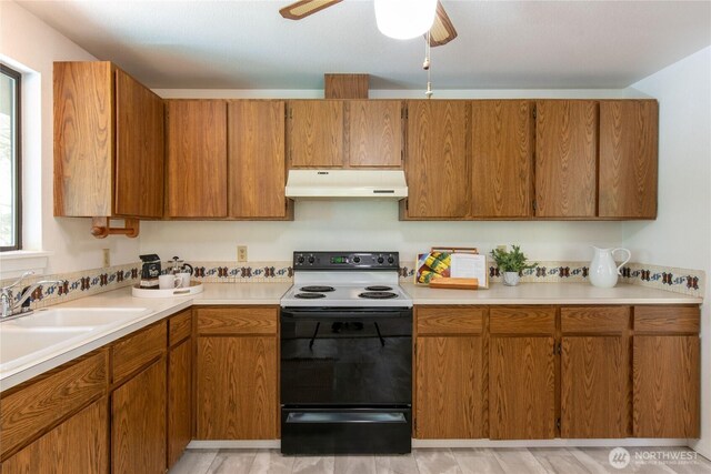 60 E Christmas Tree Pl, Belfair, WA 98528 - kitchen featuring under cabinet range hood, electric range oven, brown cabinetry, and light countertops