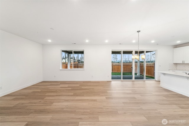 20304 150th St E, Bonney Lake, WA 98391 - unfurnished living room with recessed lighting, healthy amount of natural light, light wood-type flooring, and baseboards