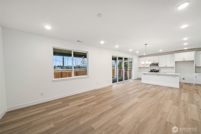 20304 150th St E, Bonney Lake, WA 98391 - unfurnished living room featuring light wood-style floors, plenty of natural light, recessed lighting, and baseboards