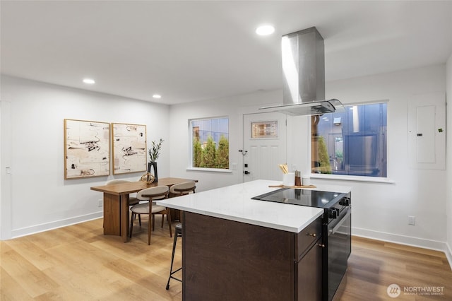 11550 22nd Ave NE, Seattle, WA 98125 - kitchen with island range hood, black electric range, electric panel, light countertops, and light wood-style floors