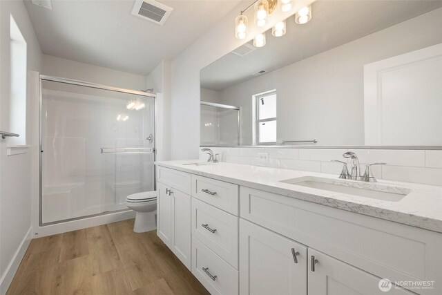 4235 W Sandy Ct, Moses Lake, WA 98837 - bathroom featuring toilet, double vanity, a shower stall, wood finished floors, and baseboards