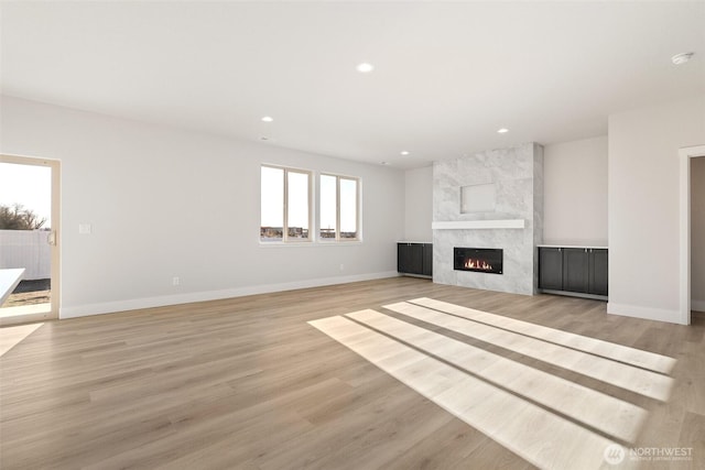 4235 W Sandy Ct, Moses Lake, WA 98837 - unfurnished living room with a premium fireplace, baseboards, recessed lighting, and light wood-style flooring