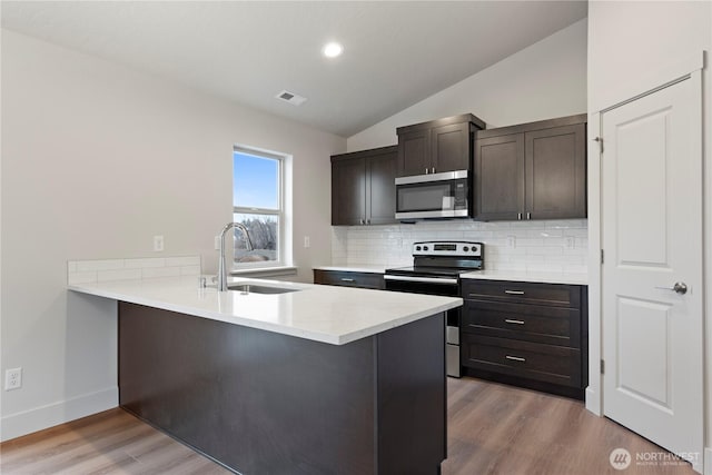 202 N Sandy Loop, Moses Lake, WA 98837 - kitchen featuring stainless steel appliances, a sink, decorative backsplash, vaulted ceiling, and light wood-style floors