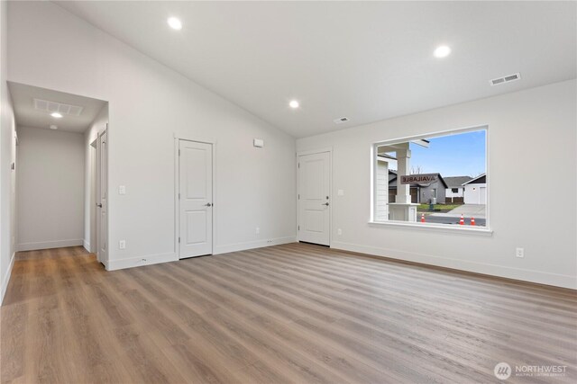 202 N Sandy Loop, Moses Lake, WA 98837 - unfurnished living room featuring lofted ceiling, wood finished floors, baseboards, and recessed lighting
