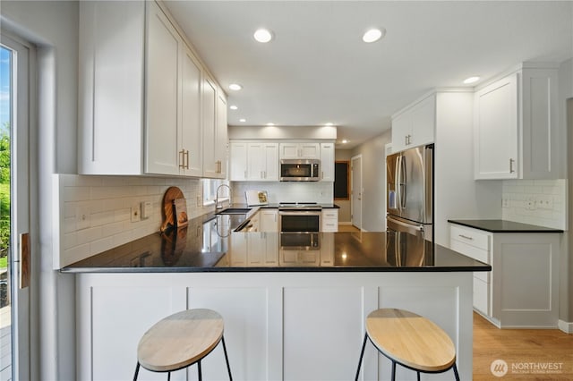 1210 Southview Dr, Walla Walla, WA 99362 - kitchen with appliances with stainless steel finishes, dark countertops, a peninsula, tasteful backsplash, and recessed lighting