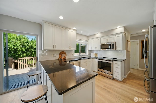 1210 Southview Dr, Walla Walla, WA 99362 - kitchen with stainless steel appliances, a peninsula, tasteful backsplash, white cabinetry, and a sink