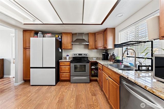 10319 SE 228th St, Kent, WA 98031 - kitchen with wall chimney range hood, appliances with stainless steel finishes, a sink, brown cabinets, and light wood-style floors