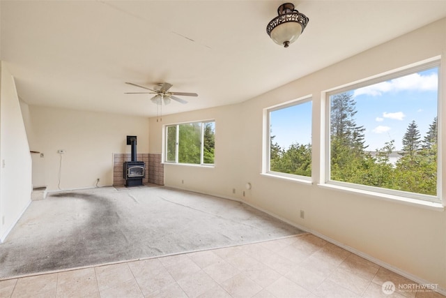 300 N St, Sequim, WA 98382 - unfurnished living room with carpet flooring, a wood stove, baseboards, and a ceiling fan