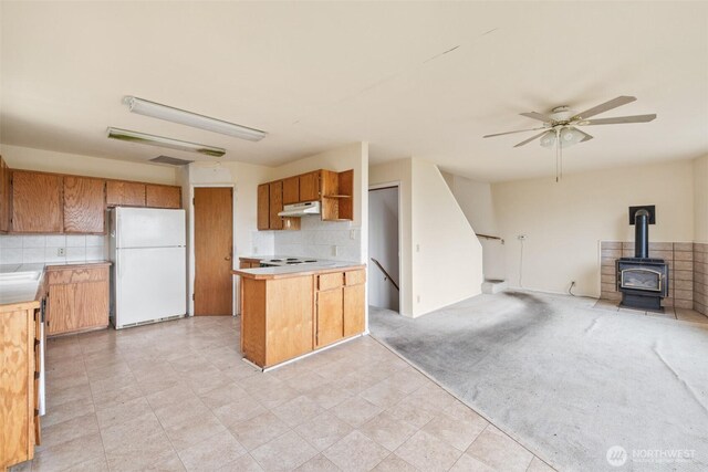 300 N St, Sequim, WA 98382 - kitchen with white appliances, open floor plan, a wood stove, under cabinet range hood, and backsplash
