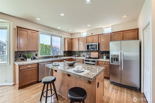 270 Kitsap Ave NE, Renton, WA 98059 - kitchen with appliances with stainless steel finishes, a sink, light wood-type flooring, a kitchen bar, and tasteful backsplash