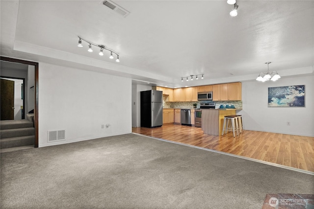 12012 County Line Rd E, Edgewood, WA 98372 - unfurnished living room with rail lighting, a chandelier, light carpet, stairway, and crown molding