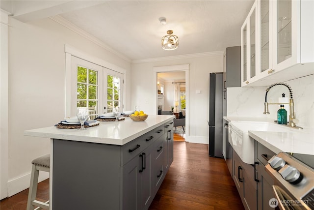 707 N Adams St, Tacoma, WA 98406 - kitchen featuring gray cabinets, dark wood finished floors, light countertops, a kitchen bar, and glass insert cabinets