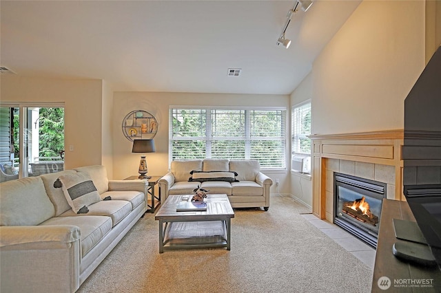 7318 Centerville Ct Unit 304, Stanwood, WA 98292 - living area featuring track lighting, a tiled fireplace, lofted ceiling, light colored carpet, and baseboards