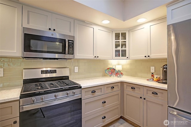 7318 Centerville Ct Unit 304, Stanwood, WA 98292 - kitchen with stainless steel appliances, glass insert cabinets, light stone counters, decorative backsplash, and recessed lighting