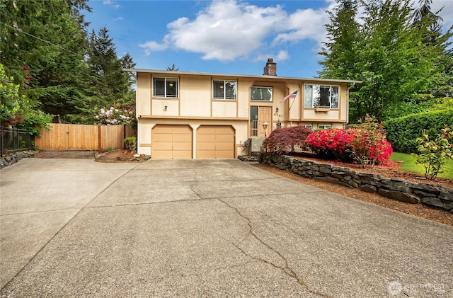 4701 161st St E, Tacoma, WA 98446 - bi-level home with a chimney, driveway, stucco siding, and a garage