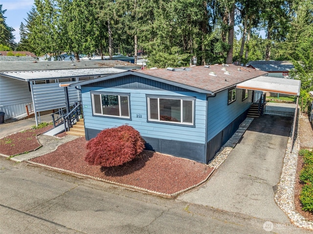 12615 113th St E Unit 249, Puyallup, WA 98374 - view of front facade with driveway, an attached carport, entry steps, and roof with shingles