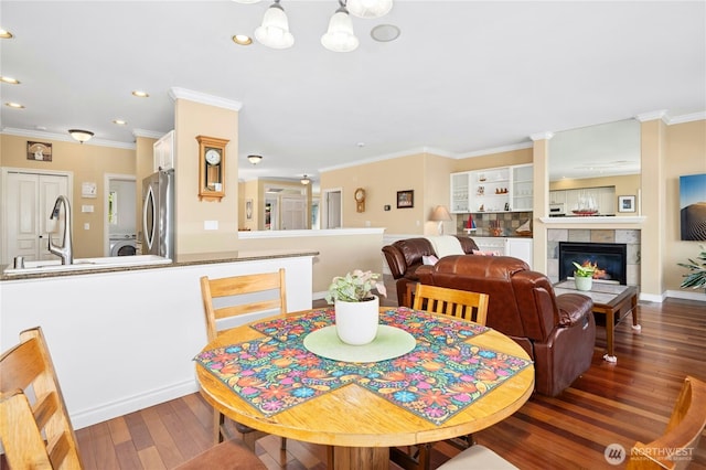 12232 SE 80th Way, Newcastle, WA 98056 - dining space featuring wood-type flooring, recessed lighting, crown molding, washer / dryer, and a tiled fireplace