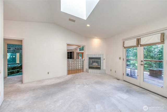 121 Switchback Rd, Orcas Island, WA 98245 - unfurnished living room featuring carpet floors, vaulted ceiling, a tile fireplace, a skylight, and french doors