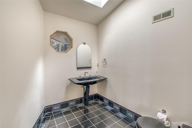 121 Switchback Rd, Orcas Island, WA 98245 - half bathroom with toilet, a skylight, baseboards, and tile patterned floors