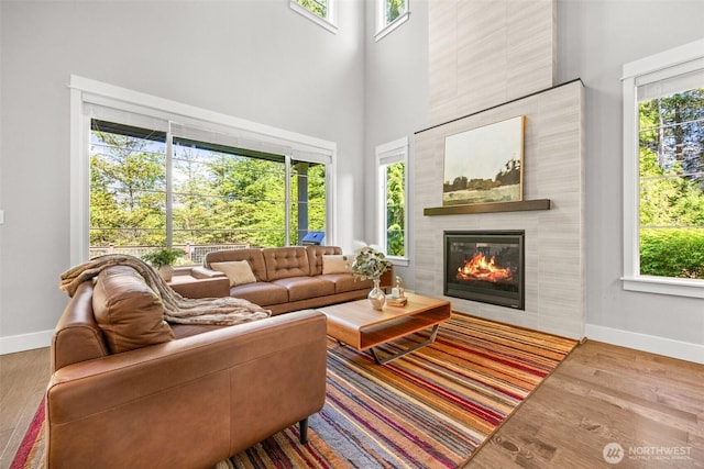 21888 SE 5th Pl, Sammamish, WA 98074 - living area with baseboards, a tiled fireplace, a high ceiling, healthy amount of natural light, and wood finished floors