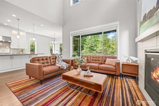21888 SE 5th Pl, Sammamish, WA 98074 - living room featuring a tiled fireplace, healthy amount of natural light, wood finished floors, recessed lighting, and a towering ceiling