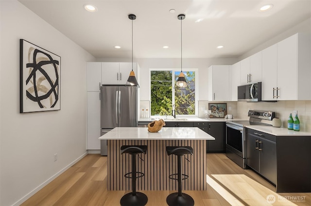 8513 19th Ave NW Unit A, Seattle, WA 98117 - kitchen with stainless steel appliances, a kitchen bar, light wood finished floors, tasteful backsplash, and recessed lighting