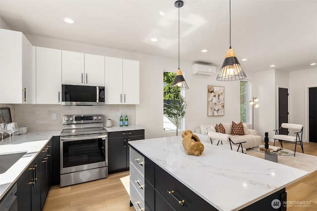 8513 19th Ave NW Unit A, Seattle, WA 98117 - kitchen with stainless steel appliances, a wall unit AC, dark cabinetry, a center island, and recessed lighting